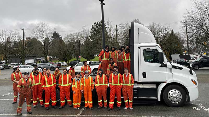 heavy mechanical trades students posing with EV truck